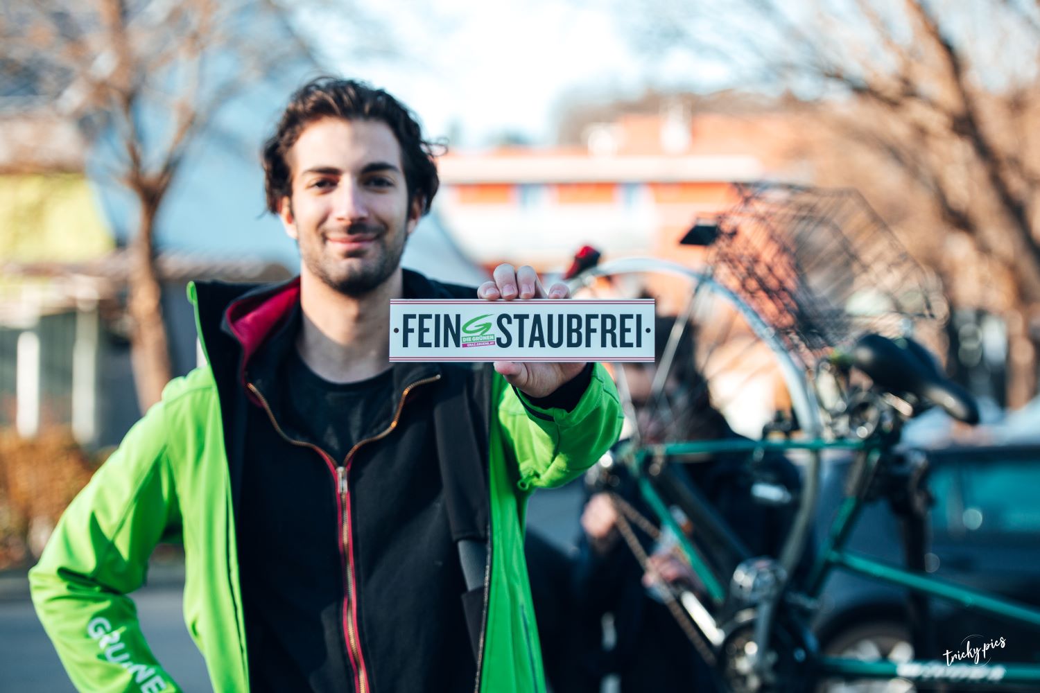 Zu sehen ist: ein junger Mann mit grüner Jacke vor einem Fahrrad.