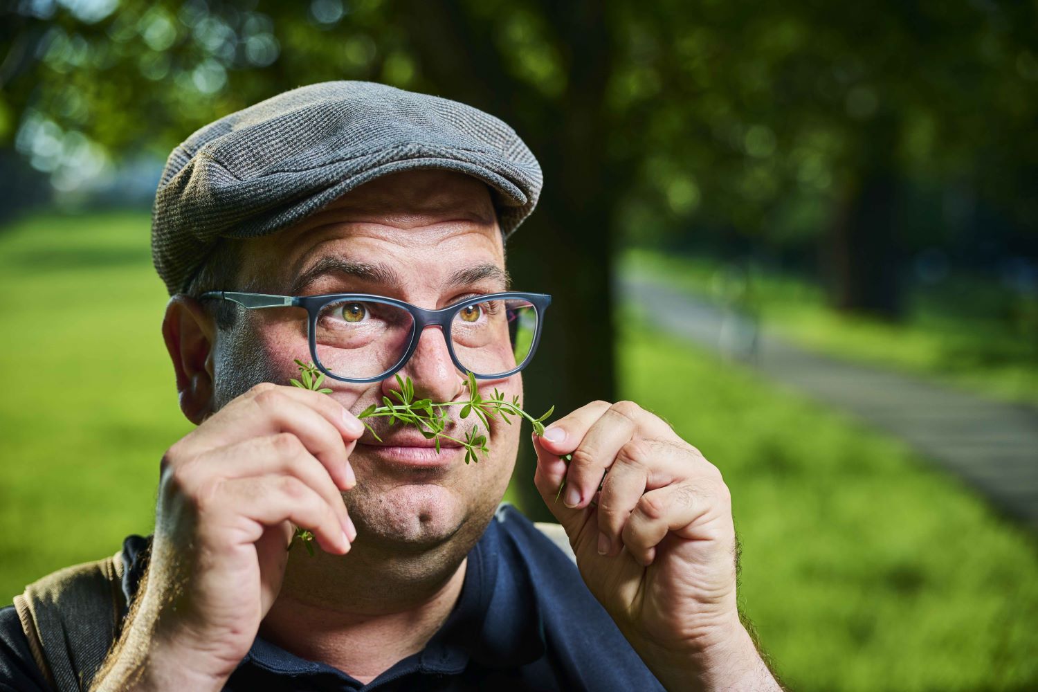 Zu sehen ist: ein Herr, der an Kräutern schnuppert.