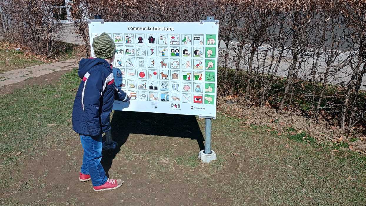 Zu sehen ist: ein Kind zeigt auf eine Kommunikationstafel in Hausmannstätten