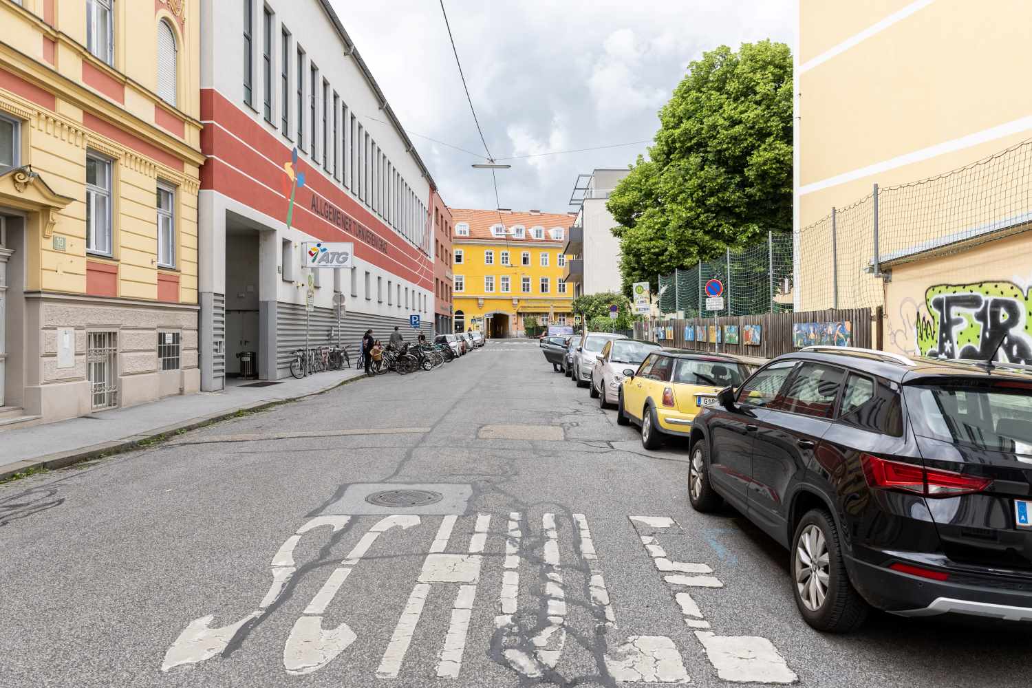 Zu sehen ist: eine Straße vor einer Schule in Jakomini
