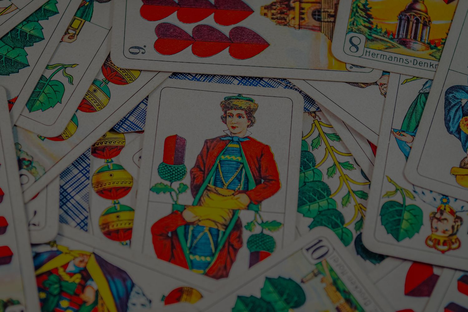 Auf dem Bild sind verschiedene Spielkarten eines Decks aus doppeldeutschen Karten zu sehen, also in den Farben Herz, Schelle, Eichel und Laub.