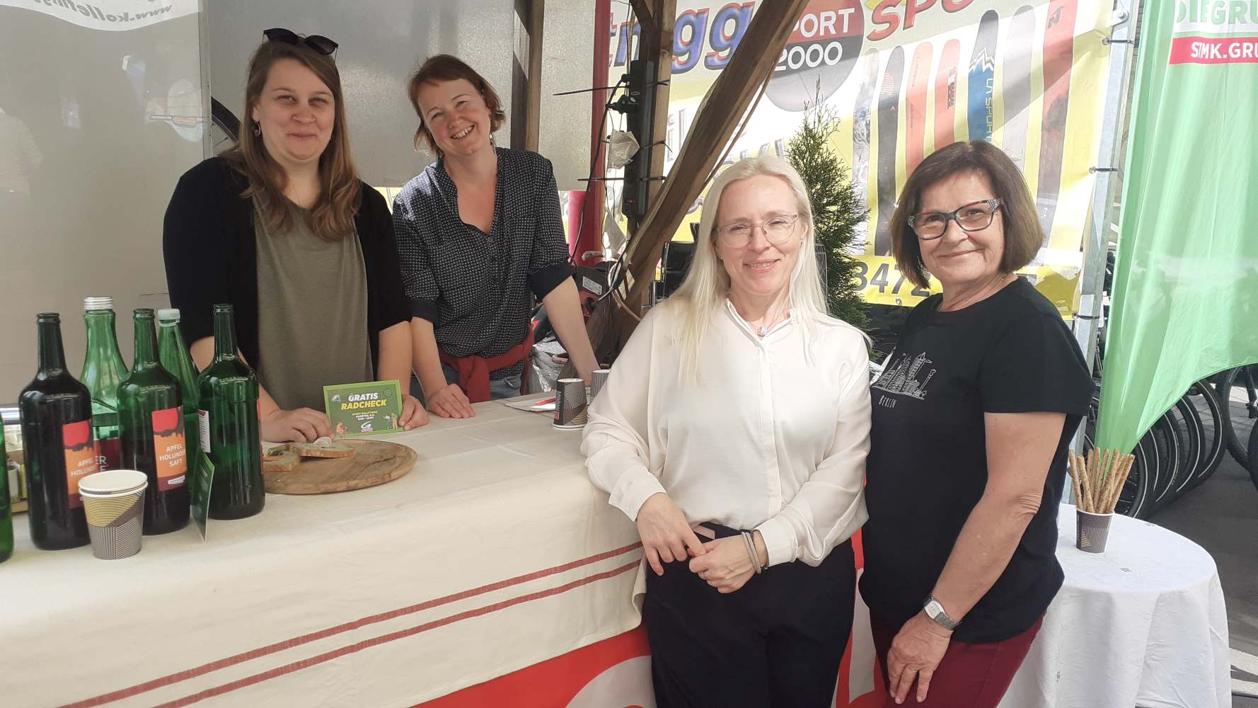 Zu sehen sind: vier Personen bei einem Messestand