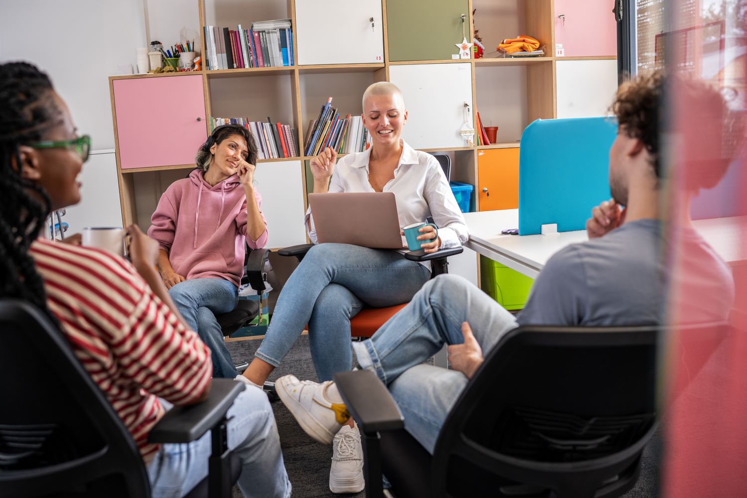 Zu sehen sind: vier junge Personen in einer Besprechung